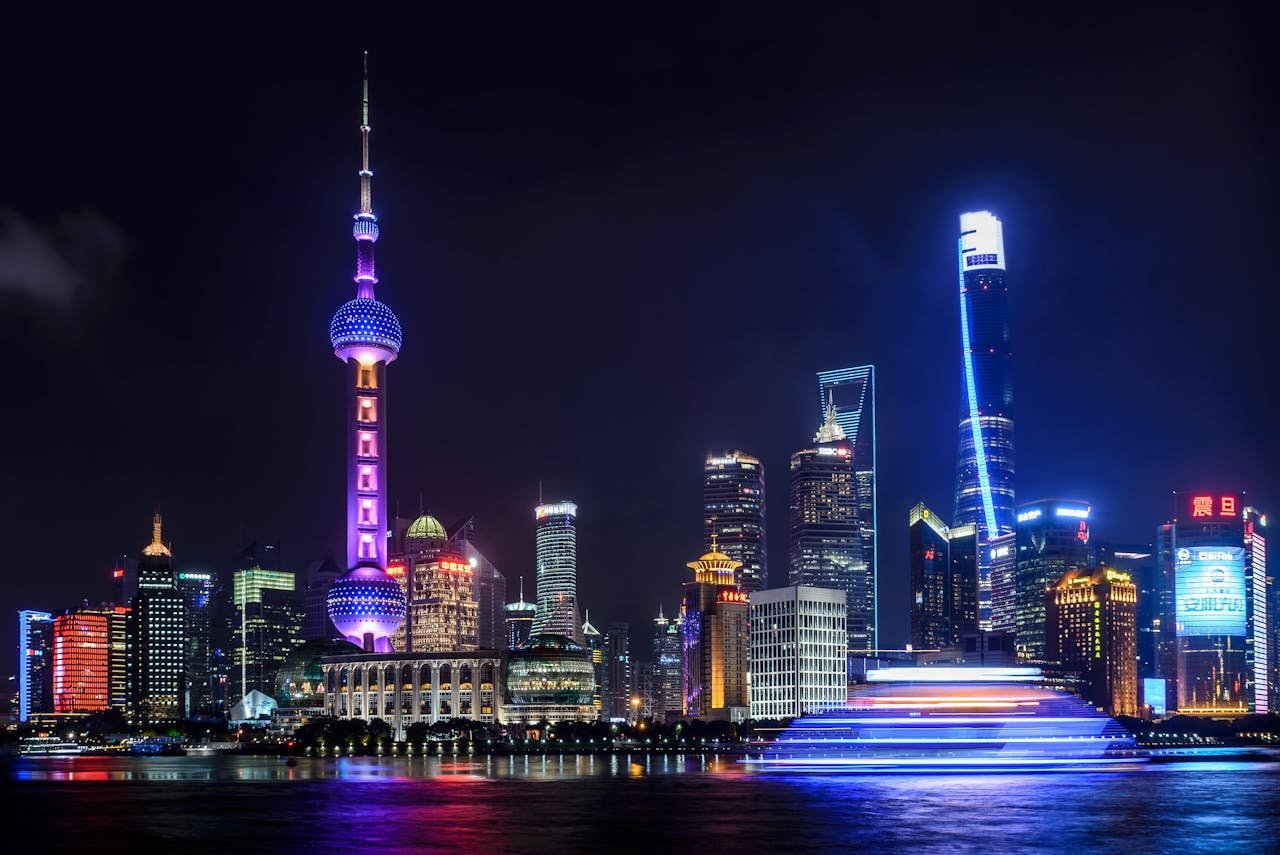 Stunning night view of Shanghai skyline with illuminated skyscrapers and the Oriental Pearl Tower reflecting in the water.